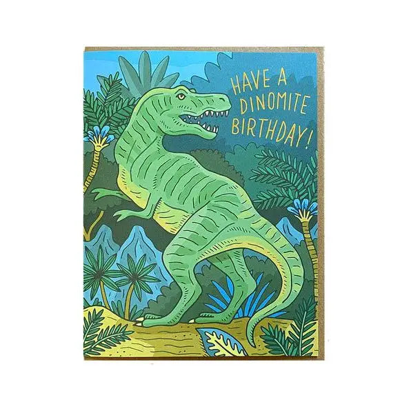 White card with blue green forest background and a green dinosaur. Yellow text reads "have a dino-mite birthday"