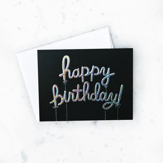 White card with black background and raised glitter balloon-shaped letters. Silver text reads "happy birthday"