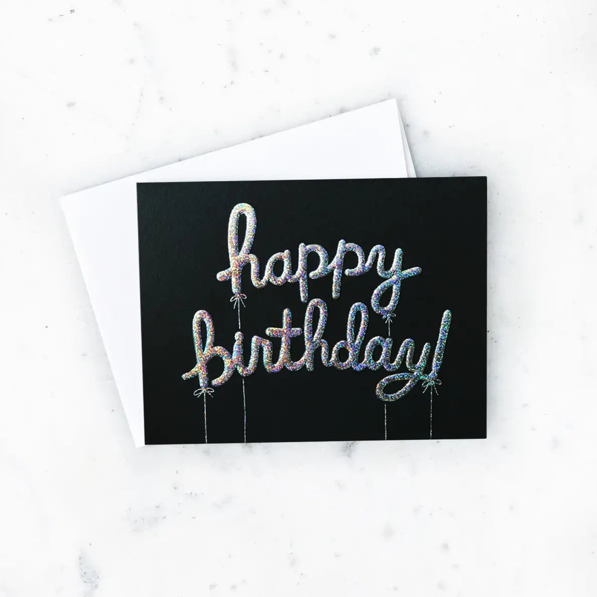 White card with black background and raised glitter balloon-shaped letters. Silver text reads "happy birthday"