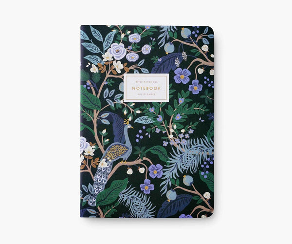 Black notebook cover decorated with blue, green, gold, and purple flowers, leaves, and peacocks. 