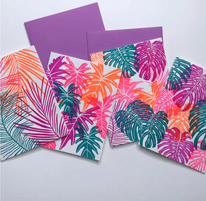 Set of four cards with white backgrounds. Each card is letterpress printed with pink, orange, purple, and teal leaves. 