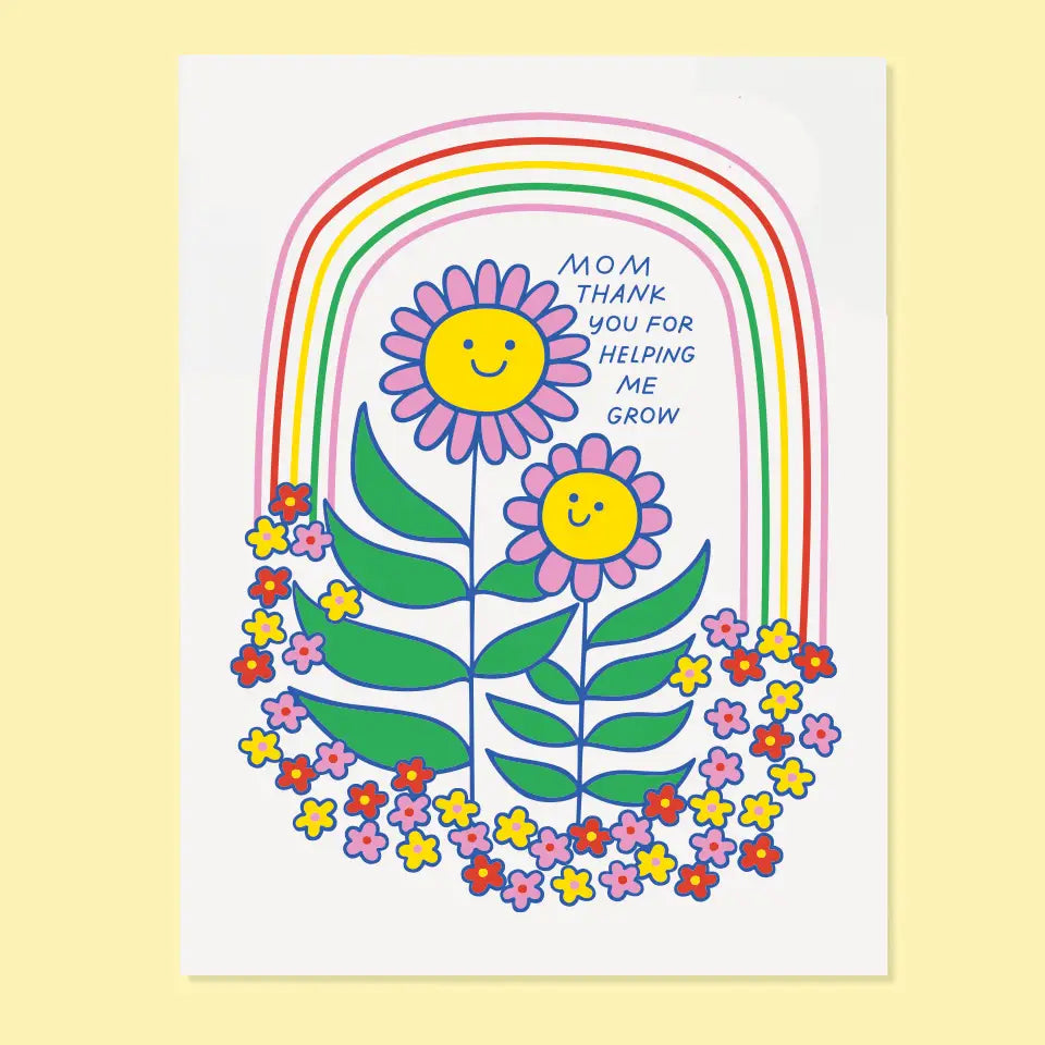 White card with a rainbow and two flowers smiling at one another. Navy text reads "mom thank you for helping me grow" 