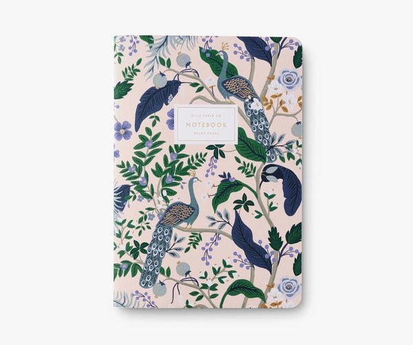 White notebook cover decorated with blue, green, gold, and purple flowers, leaves, and peacocks. 