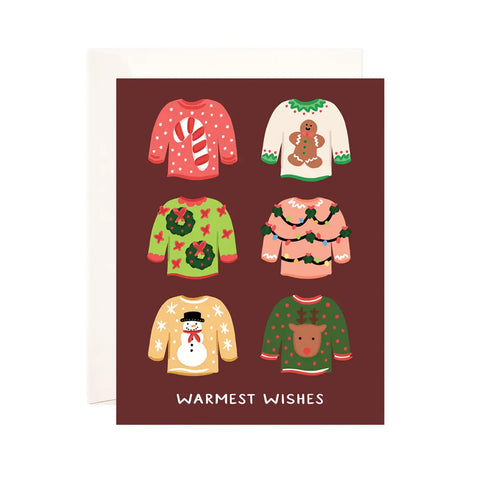 White card with maroon background. Six holiday sweater illustrations. White text reads "warmest wishes" 