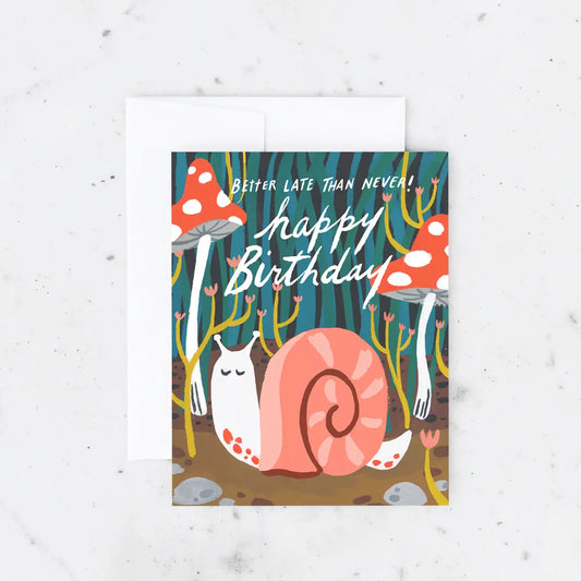 White card with blue green background, red mushrooms, and a pink and white snail. White text reads "better late than never! happy bithday"