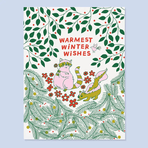 White card with green and red winter foliage and a pink and green raccoon and squirrel. Red text reads "warmest winter wishes" 