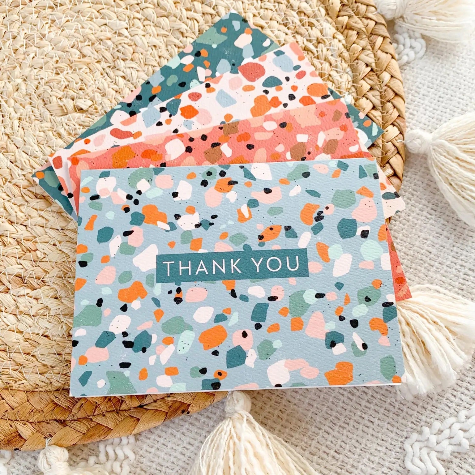 Four different cards with blue, orange, and white terrazzo pattern. Blue box with white text that reads "thank you"