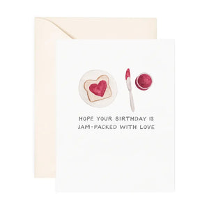 White card with drawing of red jam in a heart shape on a piece of bread. Black text reads "hope your birthday is jam-packed with love"