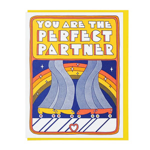 White card with illustration of two pairs of jeans and roller skates. Yellow box with white block letters inside spelling out "you are the perfect partner" 